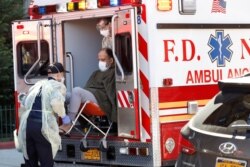 FDNY Emergency Medical Technicians (EMT) lift a patient who was identified to have coronavirus disease (COVID-19) into an ambulance in New York City, March 24, 2020.