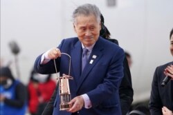 Tokyo 2020 Olympics chief Yoshiro Mori carries the Olympic flame during the Flame Arrival Ceremony at Japan Air Self-Defense Force Matsushima Base in Higashimatsushima in Miyagi Prefecture, north of Tokyo, March 20, 2020.