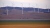 FILE - A fence is seen in front of wind turbines that are part of the Infigen Energy Capital Wind Farm located on the hills surrounding Lake George, near Canberra, Feb. 21, 2018.
