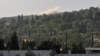 Smoke rises in the horizon as Hayat Tahrir al-Sham (HTS) jihadist group's advance toward Syrian opposition-held areas in the northern Aleppo province on Oct. 17, 2022.
