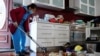 Xuan Nguyen cleans up inside a damaged home following severe flooding in the Maribyrnong suburb of Melbourne, Australia, Oct. 17, 2022. 