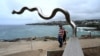 Visitors look at the sculpture 'Flooded Weir' by Vlase Nikoleski on display between Bondi and Tamarama beach as part of the Sculpture by the Sea exhibition in Sydney on Oct.21, 2022. 
