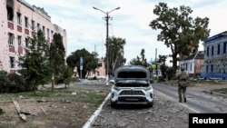 FILE PHOTO: A Ukrainian serviceman patrols a street next to damaged buildings in the town of Sudzha