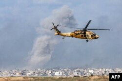 Izraelski transportni vojni helikopter američke proizvodnje "Crni soko" leti duž granice Izraela i Pojasa Gaze, nad kojom se uzdiže dim dok traju borbe, 6. decembra 2023.