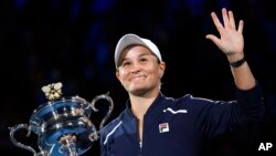 Petenis Australia Ashleigh Barty melambaikan tangan seraya memegang trofi Daphne Akhurst Memorial setelah meraih gelar Grand Slam Australia Terbuka 2022 di Melbourne, Australia, pada 29 Januari 2022. (Foto: AP/Andy Brownbill)