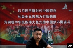 一名男子走過北京街頭宣傳習近平指示的各族人民大團結中國夢的廣告牌。（20218年9月11日）