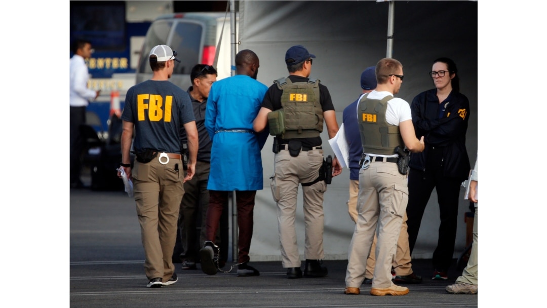 Federal agents hold a detainee, second from left, in downtown Los Angeles after predawn raids that saw dozens of people arrested in the L.A. area, Aug. 22, 2019, Most of the defendants are Nigerian nationals.