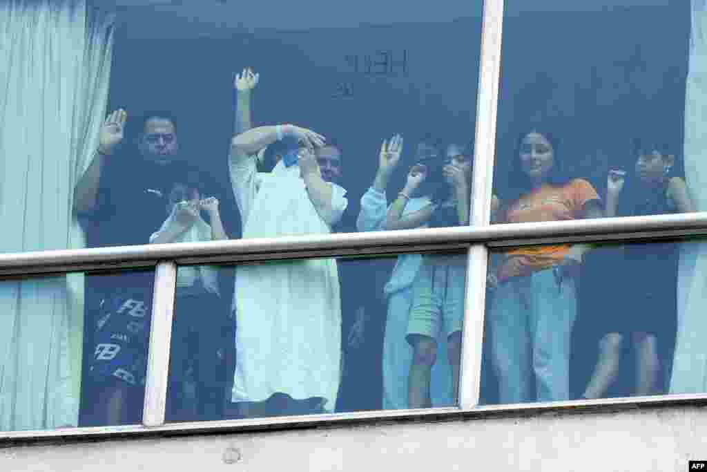 Migrants deported from the U.S. gesture as they look out the window of the Decapolis Hotel where they are temporarily staying in Panama City, Feb. 18, 2024. Panama's government denied that migrants deported by the United States who were seen holding up signs to hotel windows pleading for help were being held against their will.