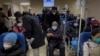 A man pushes an elderly woman past patients receiving intravenous drips in the emergency ward of a hospital, Jan. 3, 2023. 