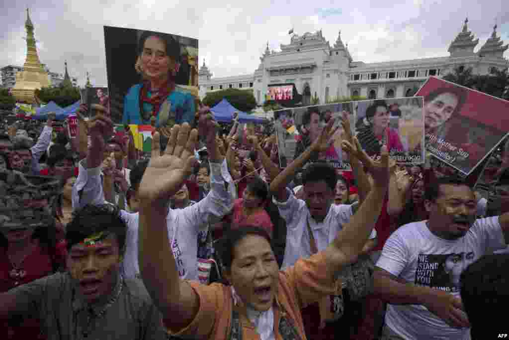 People hold the Myanmar national flag and placards as they attend a public gathering to listen to the live speech of Myanmar's State Counselor Aung San Suu Kyi in front of City Hall in Yangon.