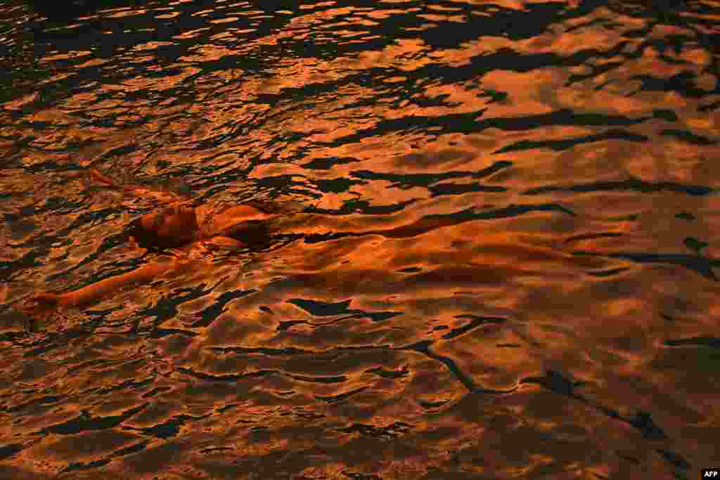 A woman cools off in a swimming pool during the last rays of sunlight in San Jose Villanueva, 25 km southwest of San Salvador, El Salvado, Sept. 3, 2017.