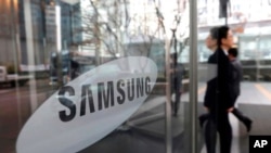 FILE - An employee walks past the Samsung Electronics Co. logo at its office in Seoul, Jan. 31, 2018. 