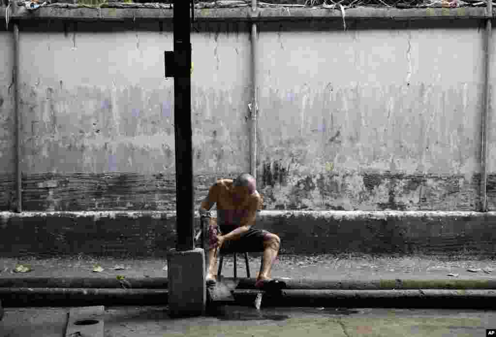 A Filipino metal worker uses a faucet to clean himself as he prepares to go home in metropolitan Manila, Philippines.