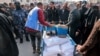 Pekerja Badan Bantuan dan Pekerjaan PBB untuk Pengungsi Palestina (UNRWA) membagikan jatah tepung dan pasokan lainnya kepada orang-orang di gudang UNRWA di Rafah di selatan Jalur Gaza pada 12 Desember 2023. (Foto: AFP)