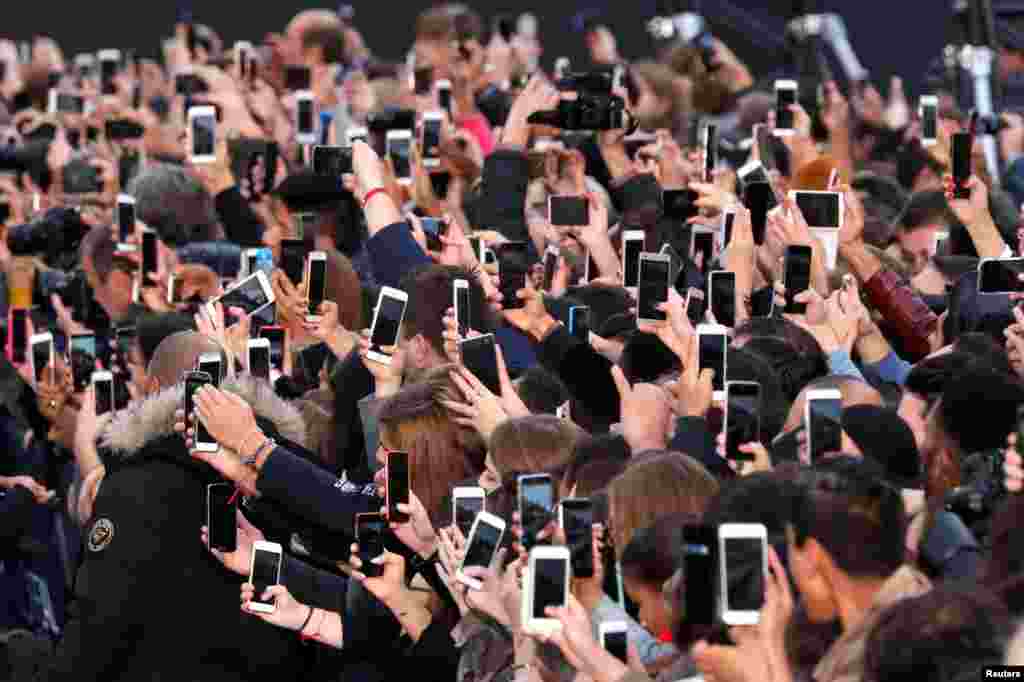 People use their smartphones to take photos of the L'Oreal fashion show on the Champs Elysees avenue during a public event organized by French cosmetics group L'Oreal in Paris, France, Oct. 1, 2017.
