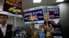 FILE - Real estate agents hold foreign properties promotion sales placards at an entrance to the China Property and Investment Show in Beijing.