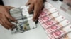 FILE - A clerk counts Chinese yuan and U.S. dollar banknotes at a branch of Bank of China in Taiyuan, China, Jan. 4, 2016. 