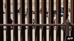 Para migran menunggu di sepanjang tembok perbatasan untuk menyerahkan diri kepada petugas patroli Dinas Bea Cukai dan Perlindungan Perbatasan AS (CBP) di El Paso, Texas, 11 Mei 2023. (Foto: Patrick T. Fallon/AFP)