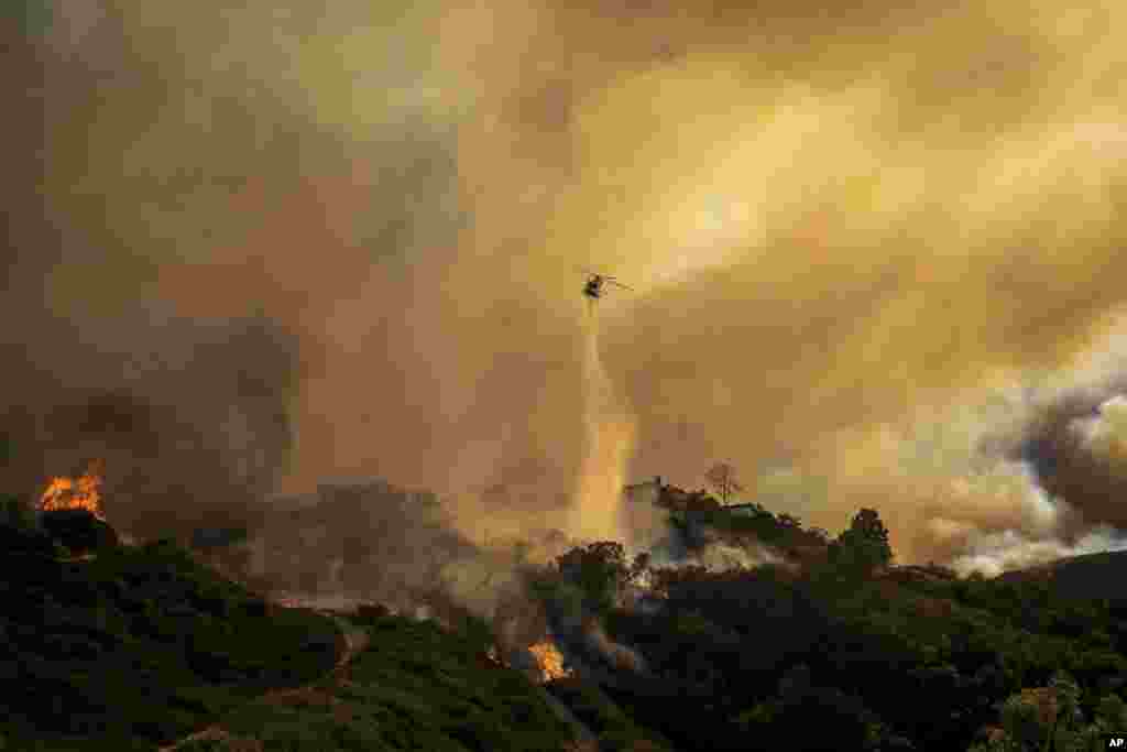 Água é lançada sobre o avanço do Palisades Fire por helicóptero no bairro de Pacific Palisades, em Los Angeles, a 7 de janeiro de 2025.