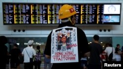 一名示威者在香港機場背負一張稱香港特首林鄭月娥為獨裁者的抗議標語。（2019年7月26日） 