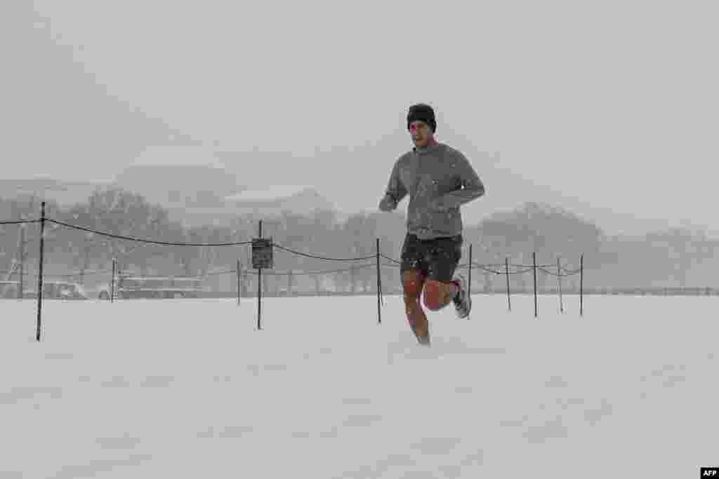 Um homem corre ao longo do National Mall enquanto a neve cai durante uma tempestade de inverno em Washington DC, a 6 de janeiro de 2025.