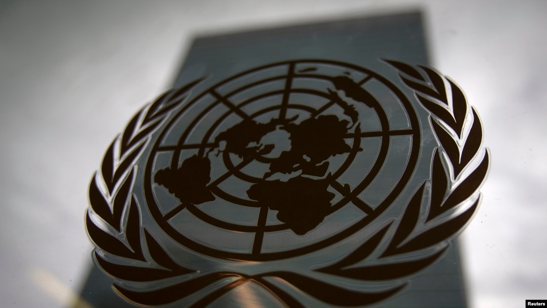 FILE - The United Nations headquarters building is pictured though a window with the UN logo in the foreground.