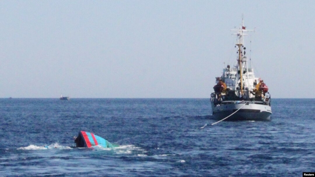A Vietnamese sinking boat (L) which was rammed and then sunk by Chinese vessels near disputed Paracels Islands, is seen near a Marine Guard ship (R) at Ly Son island of Vietnam's central Quang Ngai province May 29, 2014.