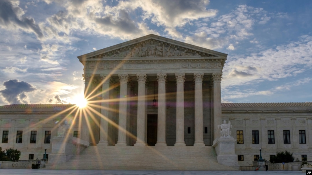 The sun flares in the camera lens as it rises behind the U.S. Supreme Court building in Washington, June 25, 2017.