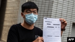 Pro-democracy activist Joshua Wong speaks to the media while holding up a bail document after leaving Central police station in Hong Kong on September 24, 2020, after being arrested for unlawful assembly related to a 2019 protest against a…