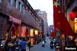 台湾金门一条街道商店旁插有中国和台湾的旗帜。（2018年8月19日）