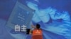 FILE - A worker checks the display panel showing a computer chip and the Chinese words for "independence" at a booth during the World AI Conference in Shanghai on July 5, 2023. Artificial intelligence competition between China and the United States is at a possible turning point.