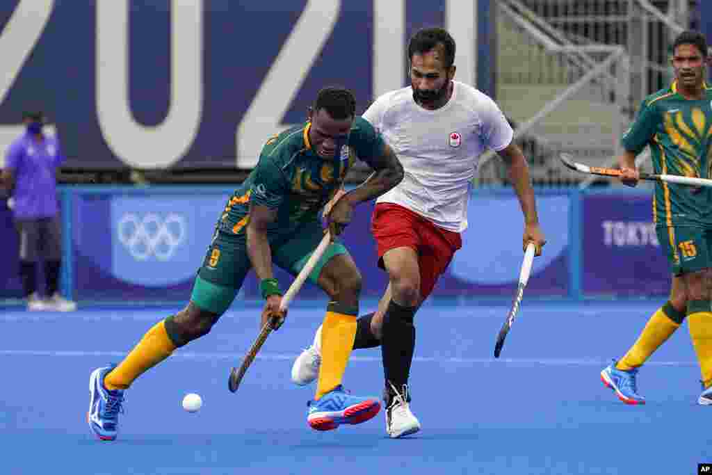 South Africa's Nduduza Peabo Lembethe (8) drives the ball against Canada's Keegan Reginald Pereira, center right, during a men's field hockey match at the 2020 Summer Olympics, Friday, July 30, 2021, in Tokyo, Japan. (AP Photo/John Minchillo)