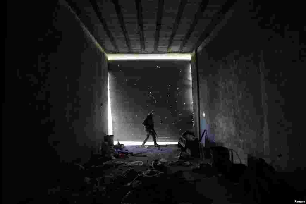 A Free Syrian Army fighter walks as he holds his weapon in a damaged shop, in the town of Tadef, Aleppo Governorate, Syria.