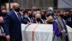 Michael Powell touches the casket of his father, former Secretary of State Colin Powell, as he walks to give a eulogy during a funeral service at the Washington National Cathedral, Nov. 5, 2021, in Washington. President Joe Biden looks on.