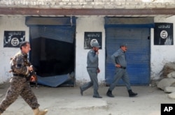 Afghan police walk past Islamic State militant flags on a wall, after an operation in the Kot district of Jalalabad province east of Kabul, Afghanistan, Aug. 1, 2016.