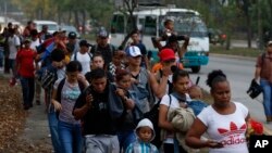 FILE - In this April 10, 2019 file photo, migrants walk at dawn as part of a new caravan of several hundred people sets off in hopes of reaching the distant United States, in San Pedro Sula, Honduras. (AP Photo/Delmer Martinez, File)