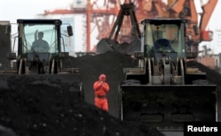 Arhiva - Zaposleni hoda između utovarivača koji se koriste za pretovar uglja uvezenog iz Severne Koreje, u Dandong luci u kineskom pograničnom gradu Dandongu, 7. decembra 2010.