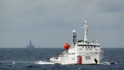 一艘中國海警船在南中國海上的一座中國海上鑽井平台旁駛過。（2014年6月13日）