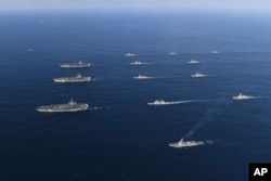 Three U.S. aircraft carriers USS Nimitz, left top, USS Ronald Reagan, left center, and USS Theodore Roosevelt, left bottom, participate with other U.S. and South Korean navy ships during the joint naval exercises between the United States and South Korea