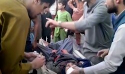 Warga Afghanistan mengangkut korban luka-luka akibat ledakan bom di bandara internasional Hamid Karzai, di Kabul, hari Kamis (26/8).