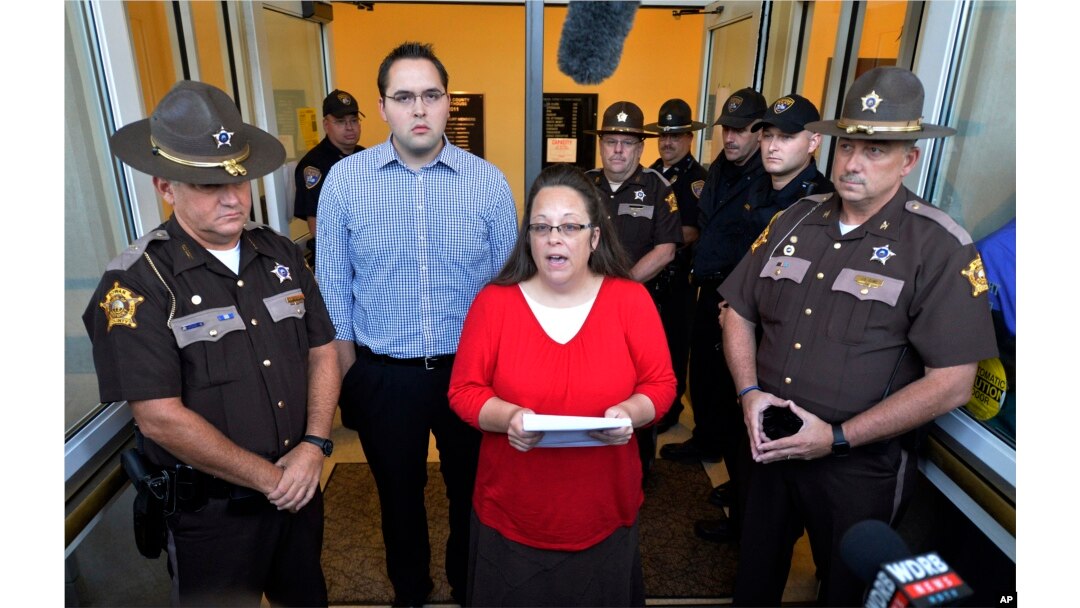 Flanked by Rowan County Sheriff's deputies, Rowan County Clerk Kim Davis, center, with her son Nathan Davis standing by her side, makes a statement to the media at the front door of the Rowan County Judicial Center in Morehead, Kentucky, Sept. 14, 2015.