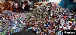 Government workers from the Bureau of Customs destroy counterfeit footwear products in Manila February 24, 2015. A government statement said over 150,000 pairs of fake shoes and slippers of various brands including Nike, Adidas, Converse, Sketchers, North