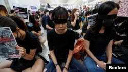 香港反送中示威者在香港國際機場靜坐示威時用黑布蒙眼，抗議警方一天前與示威者的衝突中使一名抗議者眼睛受傷。(2019年8月12日)