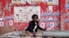 A woman prepares her stall, with election posters in the background, ahead of the presidential elections, in the suburb of Katembe, Maputo, Mozambique, Oct. 7, 2024. Voting opens across the country on Oct. 9, 2024. 