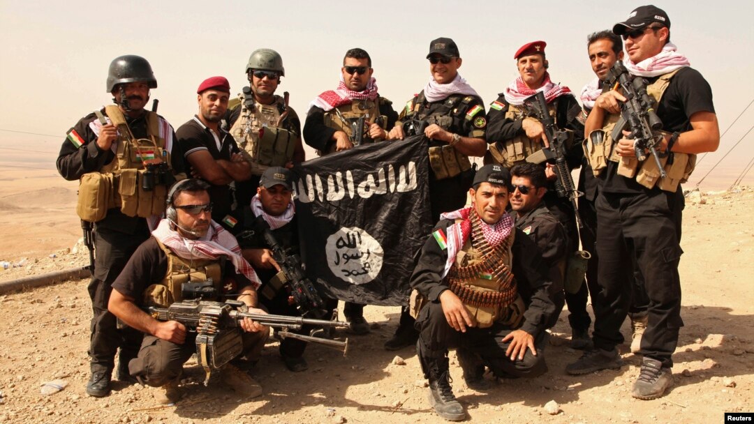 Kurdish Peshmerga fighters pose with an Islamic State flag, which they pulled down after capturing Mount Batnaya, near Zummar, Sept. 20, 2014.