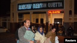 Penumpang yang diselamatkan dari kereta api setelah diserang oleh militan separatis, berjalan sambil membawa barang-barang mereka di Stasiun Kereta Api di Quetta, Balochistan, Pakistan, 12 Maret 2025. (Stringer/REUTERS)