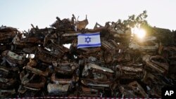 Izraelska zastava istaknuta na gomilu ugljenisanih vozila koja su bila spaljena tokom krvavog napada militanata Hamasa na Izrael 7. oktobra, ispred grada Netivota, južni Izrael, 7. anuara 2024. Vozila su sakuplena i poređana nedaleko od granice sa Gazom nakon napada.