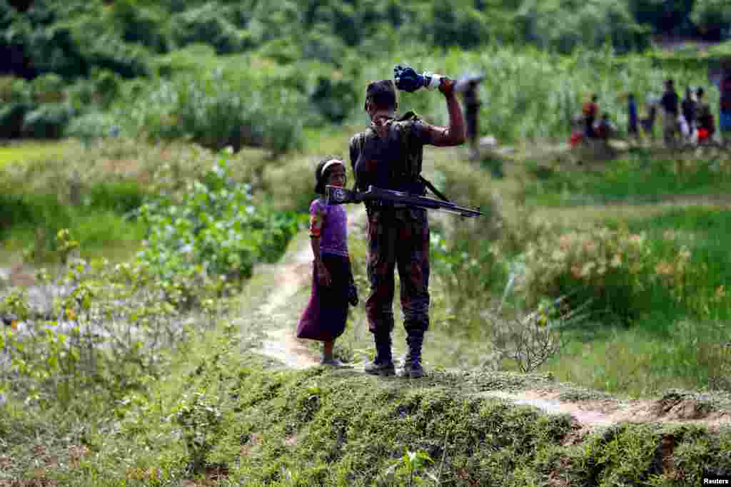A member of Border Guard Bangladesh (BGB) tells a Rohingya girl not to come on Bangladesh side, in Cox’s Bazar, Bangladesh.