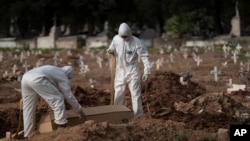 Pogrebnici u zaštitnim odelima sahranjuju sanduk sa telom 57-ogodišnjeg Pauda Hosea de Silve, žrtve koronavirusa u Rio de Ženeiru, Brazil, 5. juna 2020.