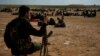 FILE - A member of U.S.-backed Syrian Democratic Forces watches over people who were evacuated out of the last territory held by Islamic State militants, outside Baghouz, Syria, March 5, 2019.